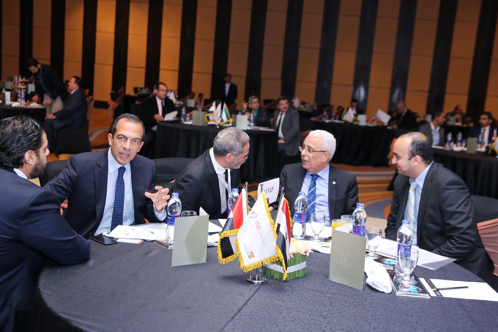Delegates in discussion at a round table with national flags