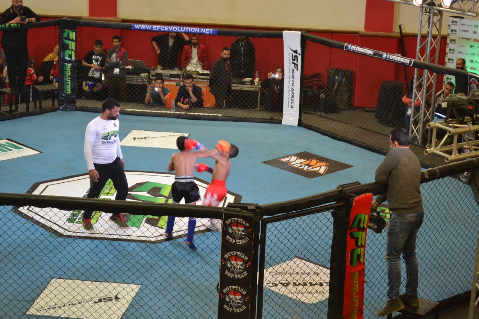 Youth combat-sports bout in the ISF-branded cage on the show floor