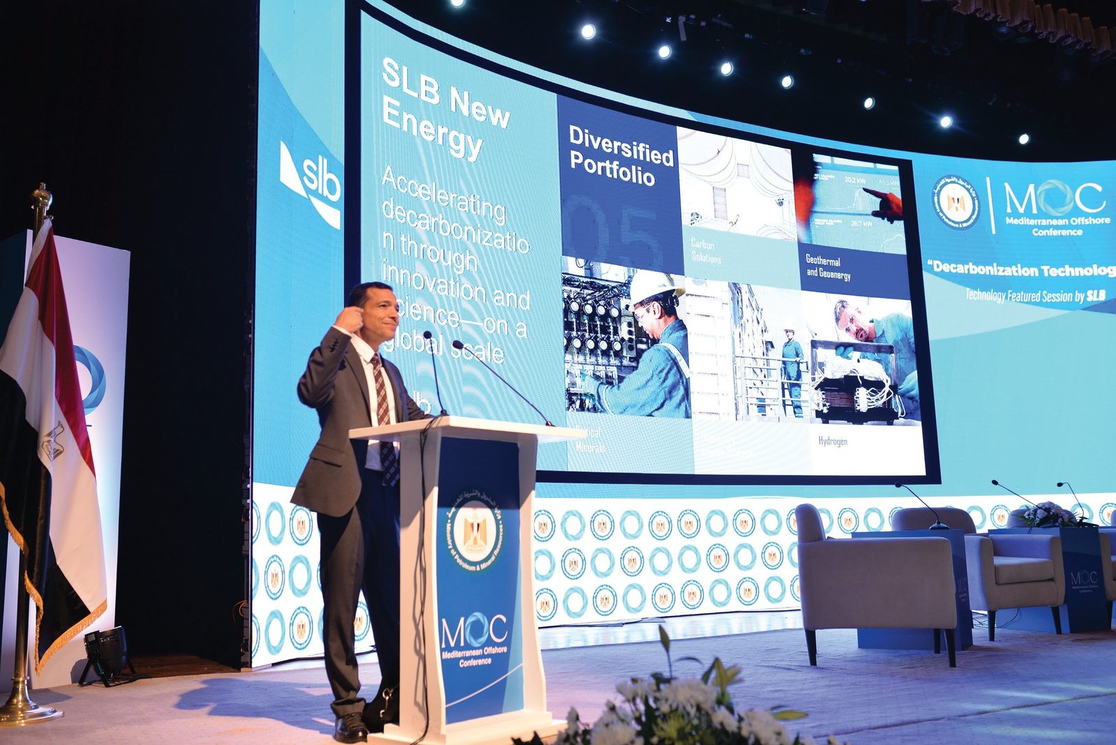 A speaker at the MOC podium in front of the branded stage set